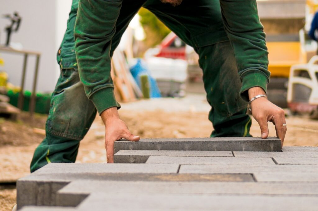 Landscaper's hands setting concrete pavers on a job site