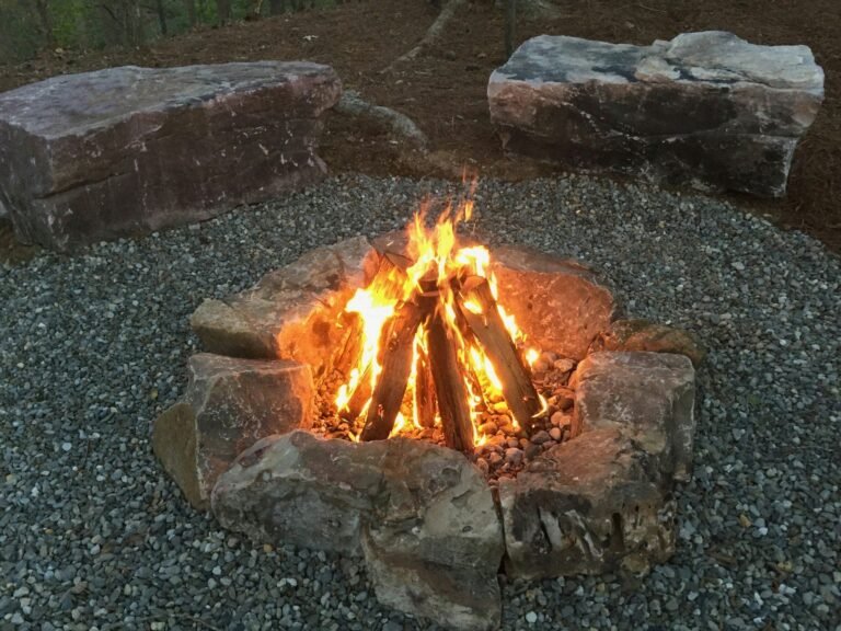 Natural stone fire pit with flames on gravel