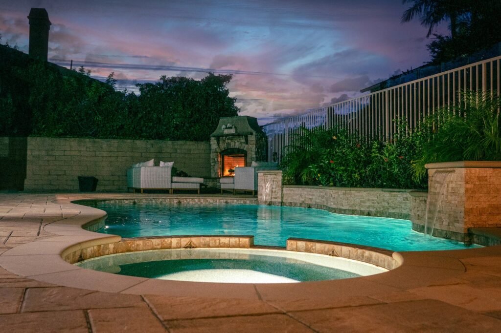 Freeform pool and spa with stone waterfall at twilight