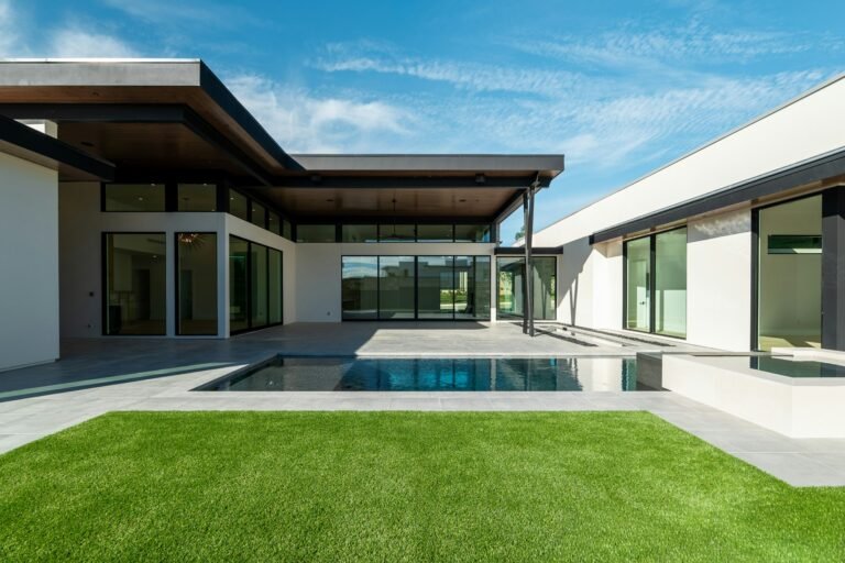 Modern home with lawn, patio and pool on a sunny day