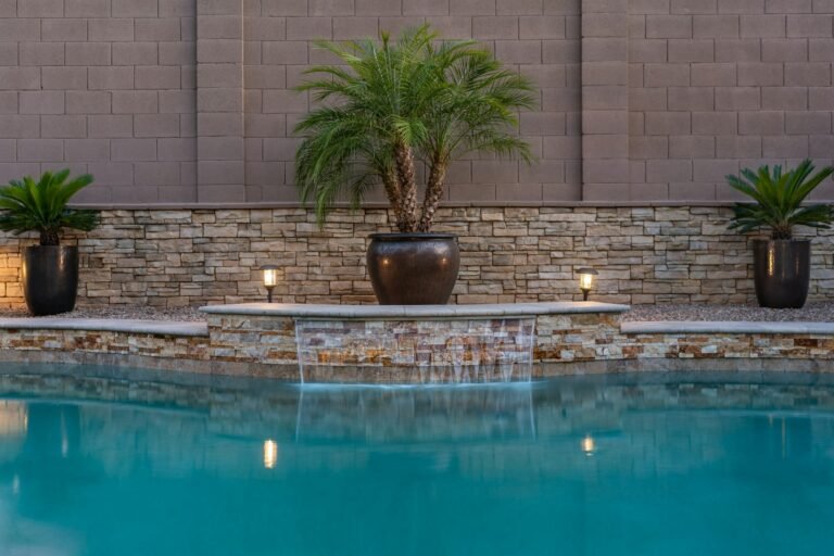 Pool with stacked stone wall, spillway and potted palms