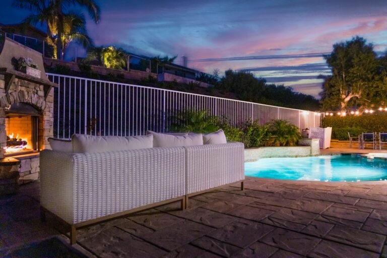 Backyard pool at twilight with outdoor fireplace and lounge seating