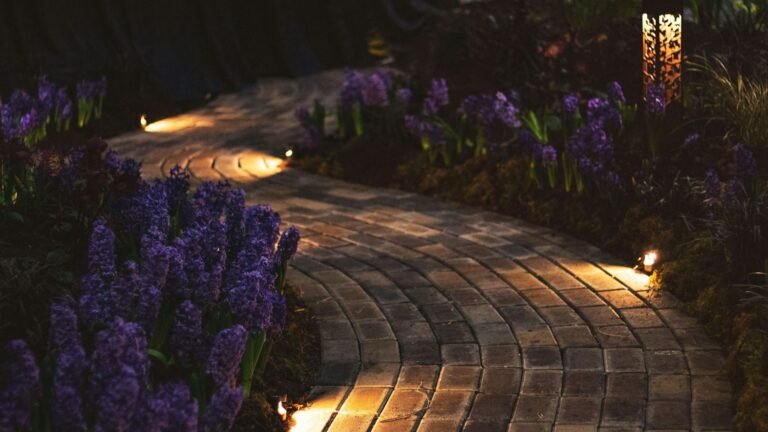 Landscape path lights glowing along a paver walkway at night