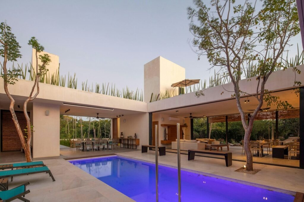 Modern open-air living area connected to a lit pool