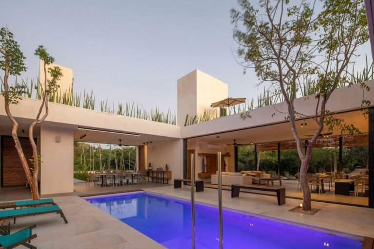 Modern open-air living area connected to a lit pool