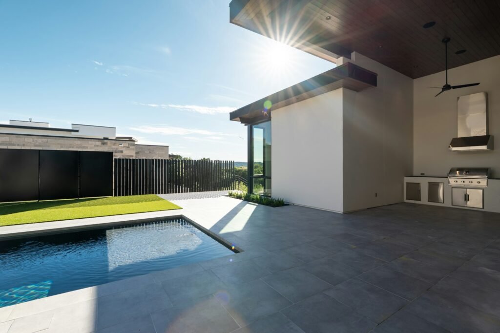 Modern covered patio with outdoor kitchen beside pool