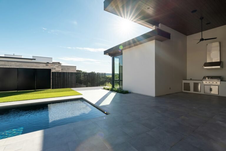 Modern covered patio with outdoor kitchen beside pool