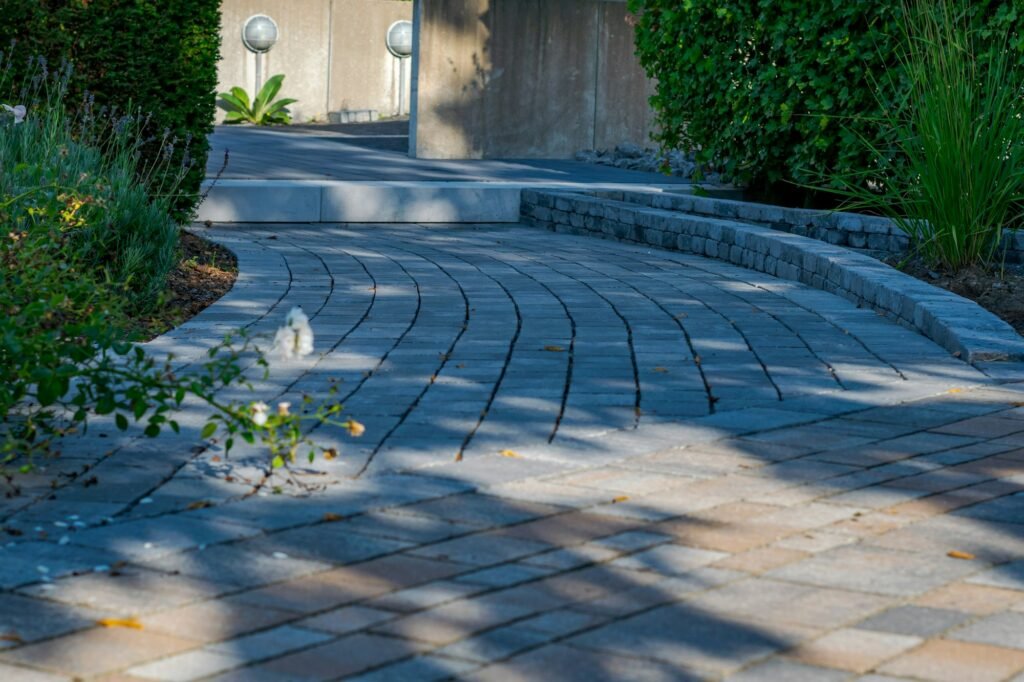 Curved gray paver walkway lined with garden plantings