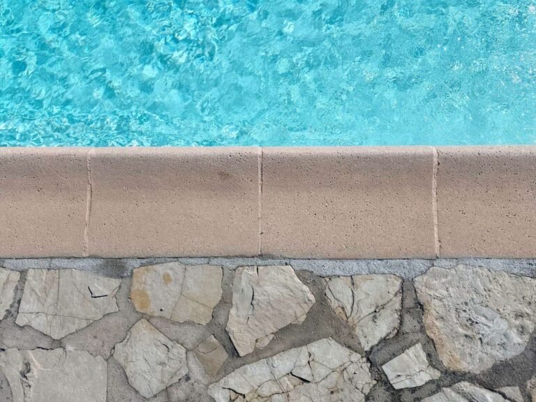 Pool edge with rounded coping above natural stone